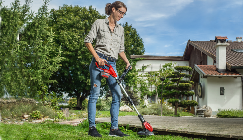 woman working with a cordless lawn trimmer