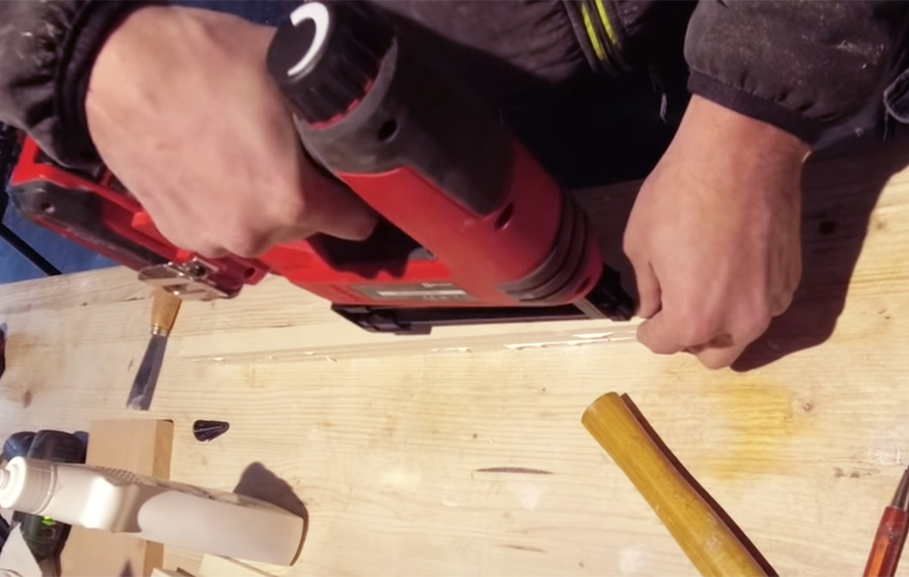 Mann befestigt Holzleisten mit einem Akkutacker auf einer Werkbank.