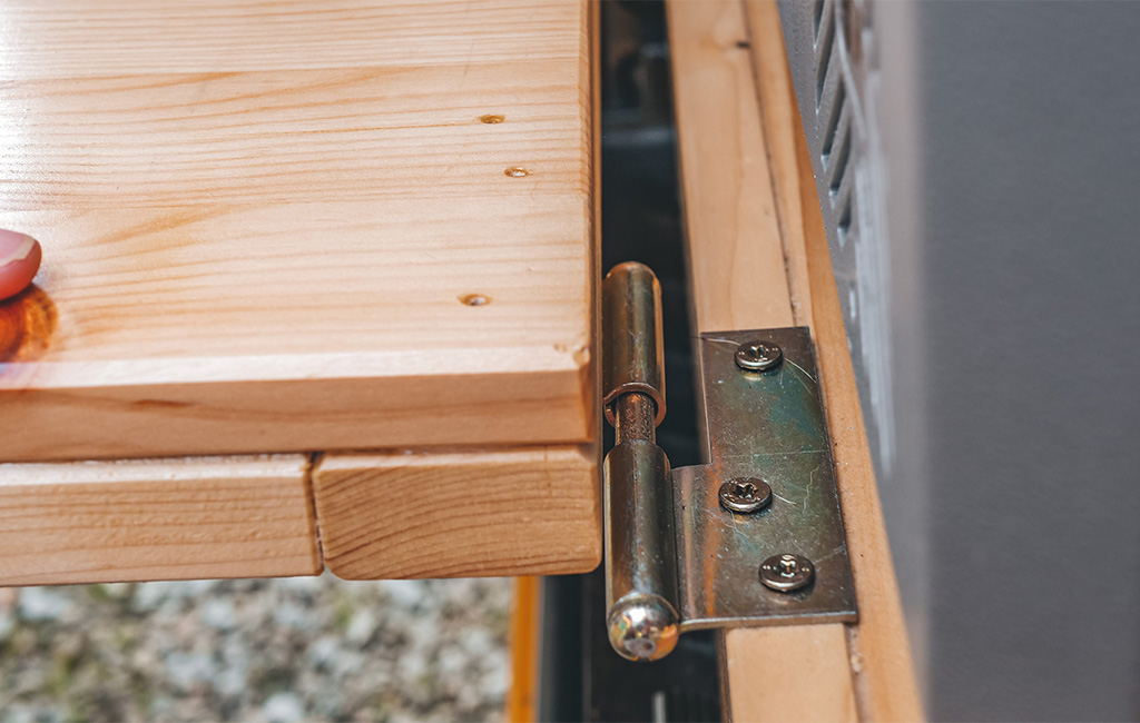 Nahaufnahme eines Metallscharniers, das zwei Holzplatten miteinander verbindet.