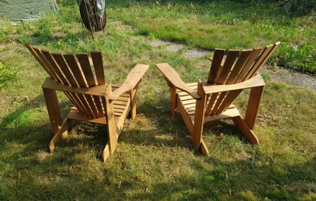 Zwei selbstgebaute Holz-Gartenstühle stehen nebeneinander auf einer Wiese.
