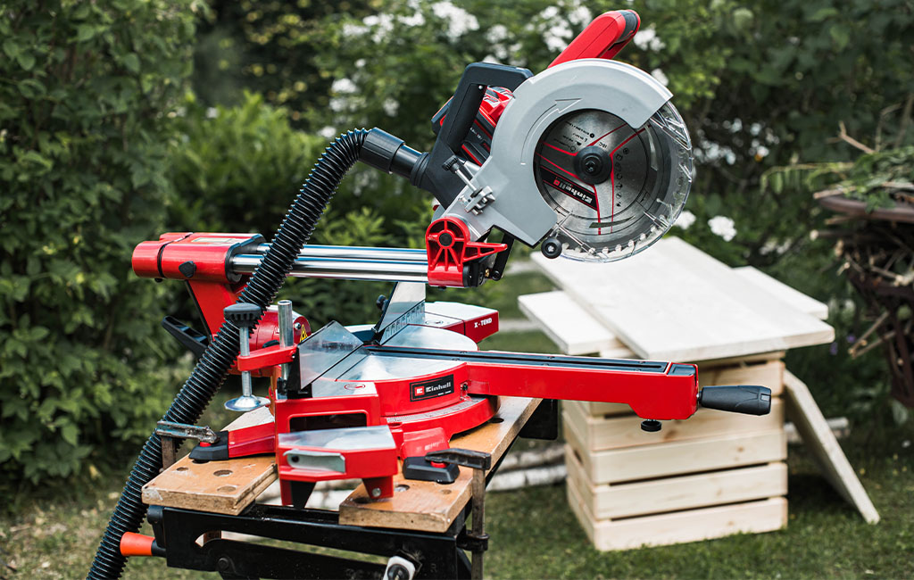 Eine Einhell Zug-Kapp-Gehrungssäge steht einsatzbereit auf einem Werktisch im Garten.